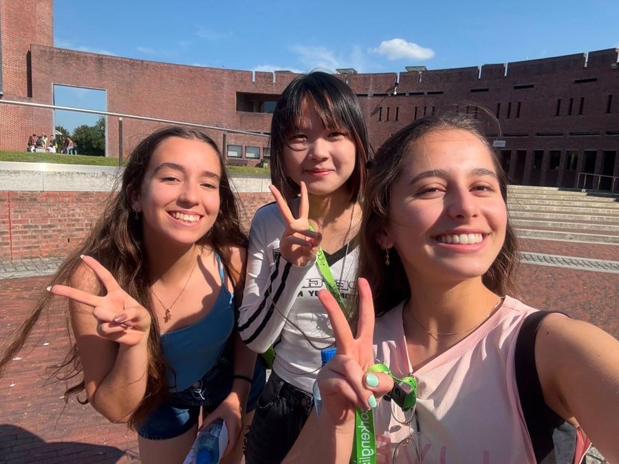 Estudantes de vários países sorrindo juntos no campus do Summer Camp, com os crachás verdes